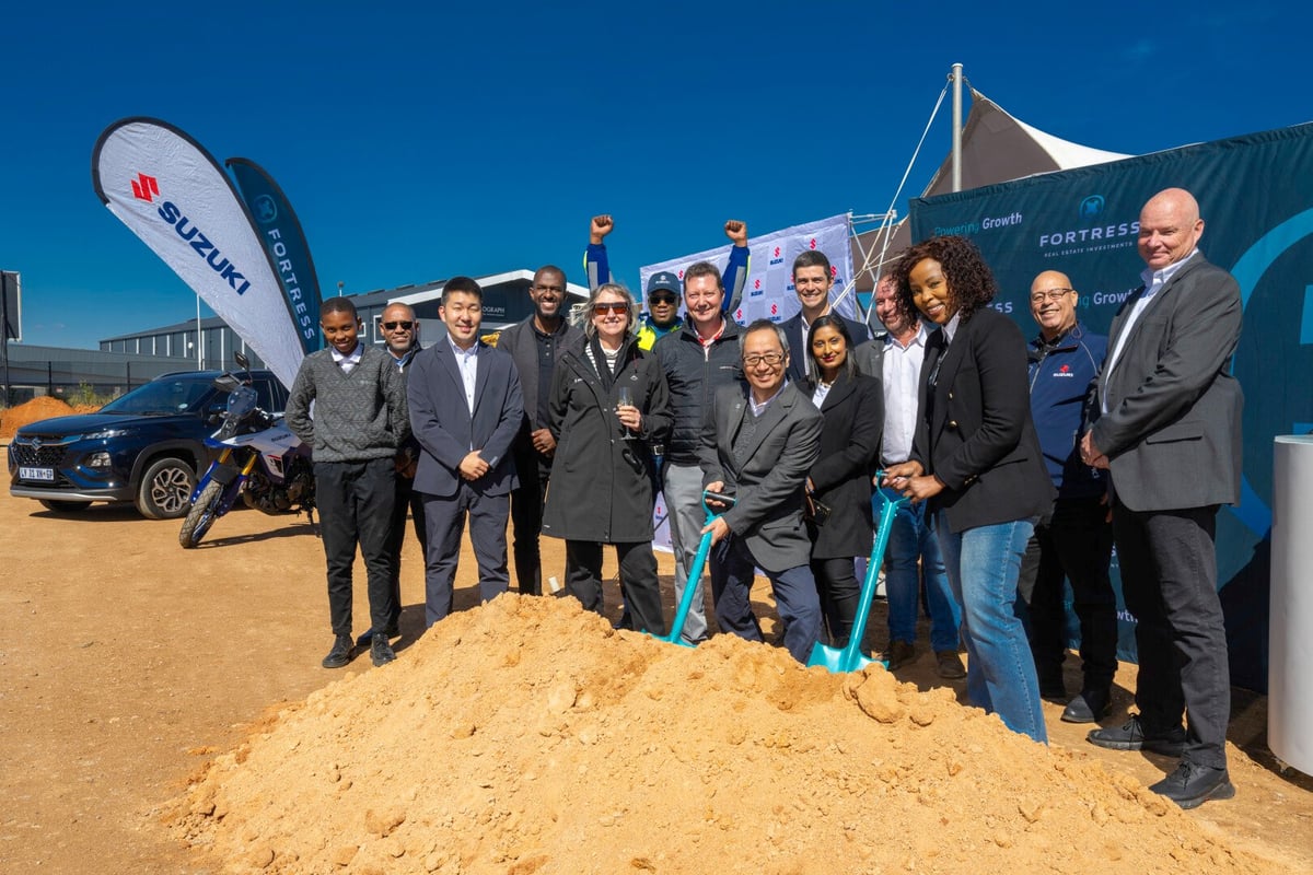 Suzuki team holding spades and digging sand.