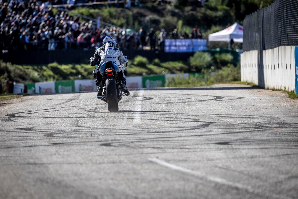 Motorbike on racetrack with people in the stalls