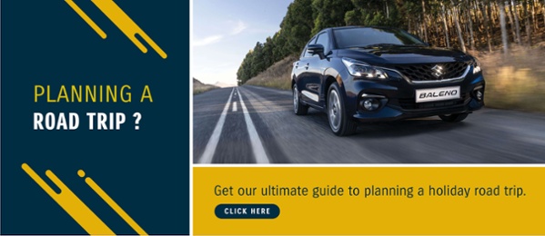 Black Suzuki Baleno driving on the tar road with the words planning a road trip? click to action for downloading the ultimate guide to planning a holiday road trip